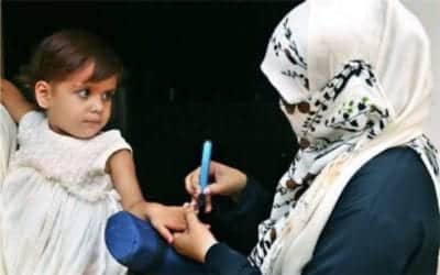 Child in Pakistan having her pinkie finger marked